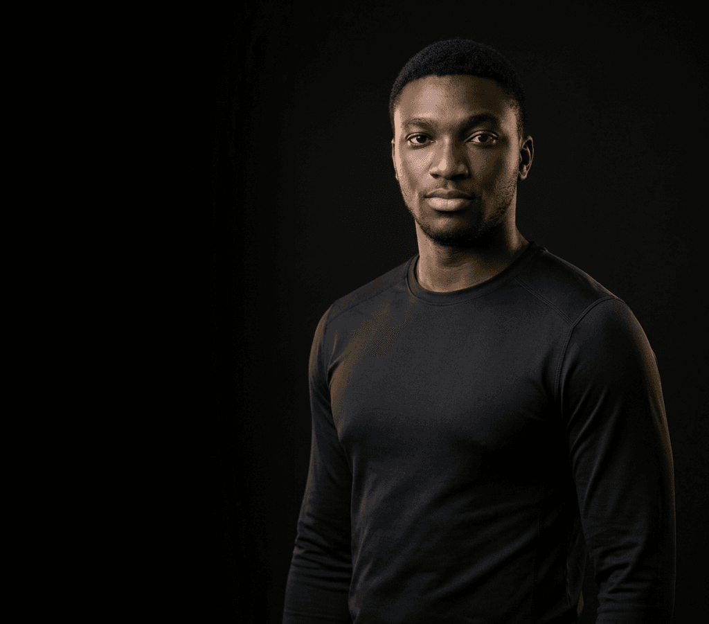 Samuel Oyenuga in a black long-sleeve top against a dark studio background
